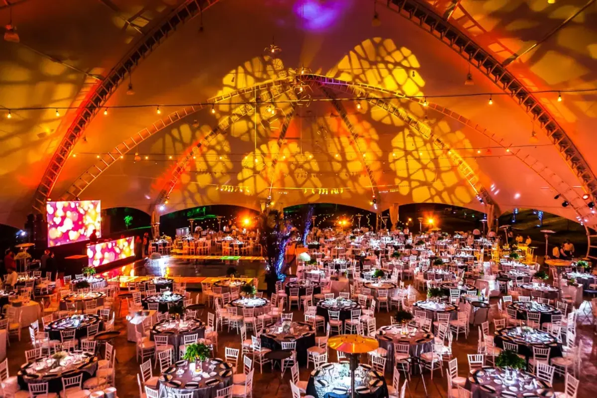 Carpa con proyección de luz cálida sobre un banquete