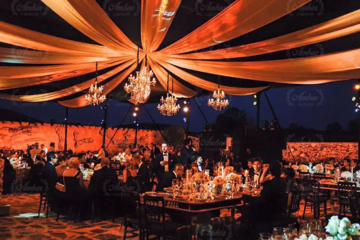 Telas color ámbar con candiles sobre un banquete al aire libre